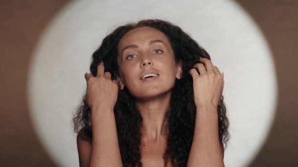 白い円形の光を持つオレンジ色の背景にあるセミノードの女性 長い曲がった髪の女性が風に揺れている ヘアスタイリング ケアのコンセプト — ストック動画