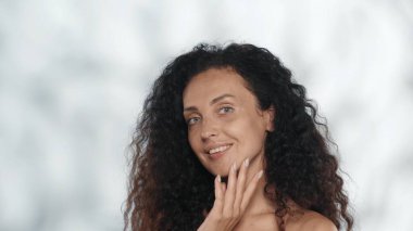 Normal hatları ve mükemmel cildi olan bir seminer kadınının portresi. Stüdyodaki gri arka planda röfleli kıvırcık kadın. Yüz geliştirme. Doğal güzellik kavramı, plastik.