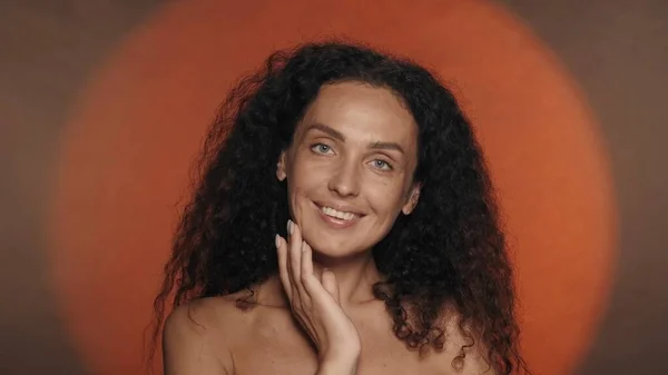 セミナーの女性の肖像画は 定期的な特徴と完璧な肌が近づいています オレンジ色のバックグラウンドのスタジオのカーリー女性 再建する 自然美のコンセプト — ストック写真
