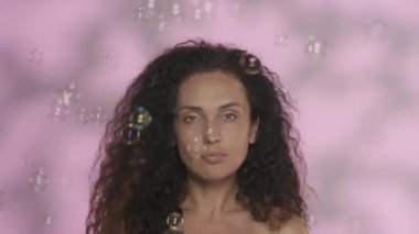 Stüdyoda, arka planda pembe renkli, yakın plan resimli bir kadın resmi. Kadın etrafında dönen sabun köpüklerini fırçalıyor. Güzellik, kozmetoloji, cilt bakımı, spa