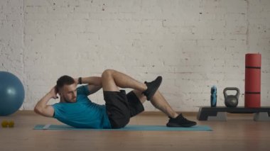 Atletik erkek fitness koçu çevrimiçi dersler için ev stüdyosunda egzersiz yapıyor. Spor kıyafetli bir adam vücut kasları egzersizi yapıyor. Sağlık hizmetleri kavramı.