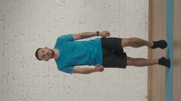 垂直录像 个人运动训练在家里 运动健美教练在家庭工作室为在线课程做运动 穿着运动服的男子膝盖高高地跳着 分身跳着热身 — 图库视频影像