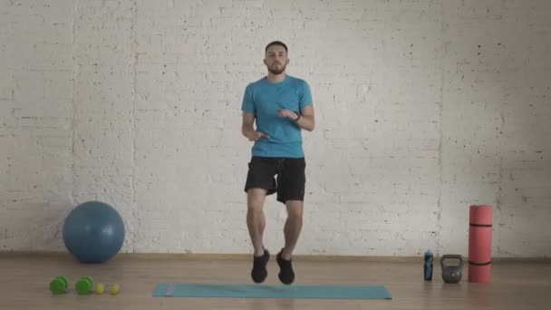 个人运动训练在家里 运动健美教练在家庭工作室为在线课程做运动 穿着运动服的男子跳高膝以代替有氧运动热身 保健概念 — 图库视频影像