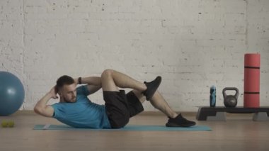 Atletik erkek fitness koçu çevrimiçi dersler için ev stüdyosunda egzersiz yapıyor. Spor kıyafetli bir adam vücut kasları egzersizi yapıyor. Sağlık sigortası konsepti. HDR BT2020 HLG Malzemesi.