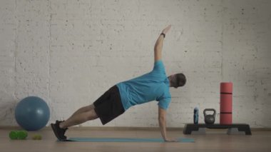 Yakın plan çekim. Evde kişisel spor eğitimleri. Atletik erkek fitness koçu çevrimiçi dersler için ev stüdyosunda egzersiz yapıyor. Spor kıyafetli bir adam aktif, dirsek tahtası egzersizi yapıyor. HDR BT2020 HLG