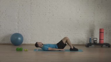 Spor eğitimleri kapalı alanlarda. Atletik erkek fitness koçu çevrimiçi dersler için ev stüdyosunda egzersiz yapıyor. Spor kıyafetli bir adam vücut kaslarını çalıştırıyor. Sağlık sigortası konsepti. HDR BT2020 HLG