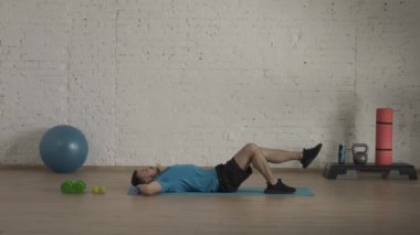 Spor iç mekanda. Atletik erkek fitness koçu çevrimiçi dersler için ev stüdyosunda egzersiz yapıyor. Spor kıyafetli bir adam vücut kasları egzersizi yapıyor. Sağlık sigortası konsepti. HDR BT2020 HLG Malzemesi