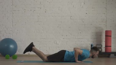 Yakın plan çekim. Atletik erkek fitness koçu çevrimiçi dersler için ev stüdyosunda egzersiz yapıyor. Spor kıyafetli bir adam diz şınavı egzersizi yapıyor. Sağlık sigortası konsepti. HDR BT2020 HLG Malzemesi.