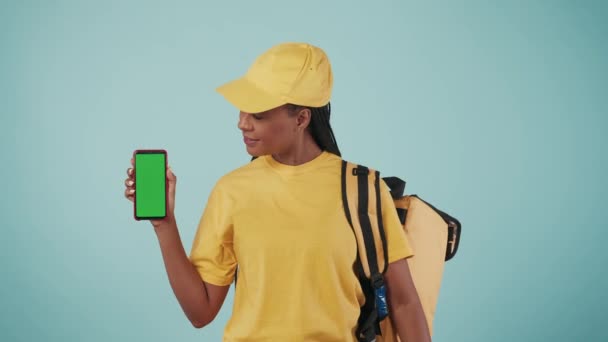 快递服务的概念 一个提着背包 冰箱和智能手机的送货妇女的画像 露出大拇指 被蓝色背景隔离了广告区 工作空间模型 — 图库视频影像
