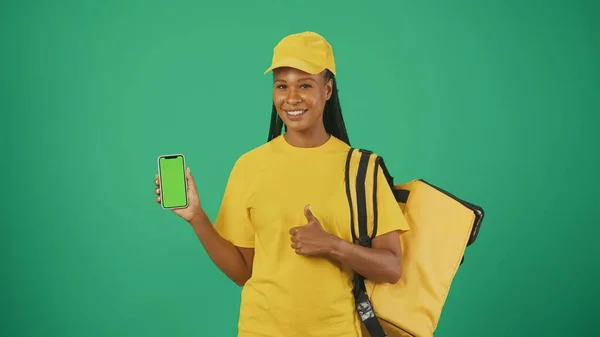 一个头戴黄色帽子 头戴手提式背负式冰箱和智能手机的送货妇女的画像 大拇指向上看 广告区 工作空间模型 — 图库照片