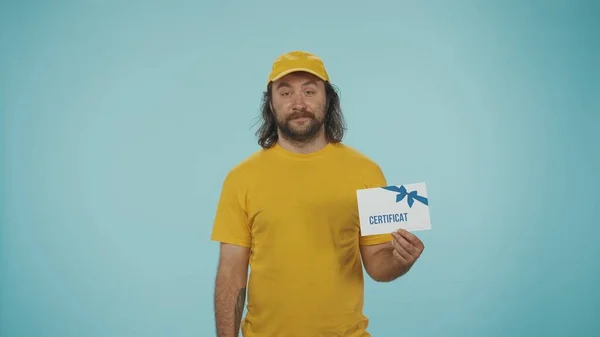 카메라를 인증서를 노란색 모자와 셔츠에 남자의 초상화 파란색 배경에 — 스톡 사진