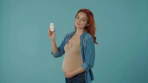 青い背景にスタジオにビタミン瓶を塗った妊婦の肖像画 妊娠期間中の医療と出生前のビタミン 妊娠中の病気や薬について — ストック写真
