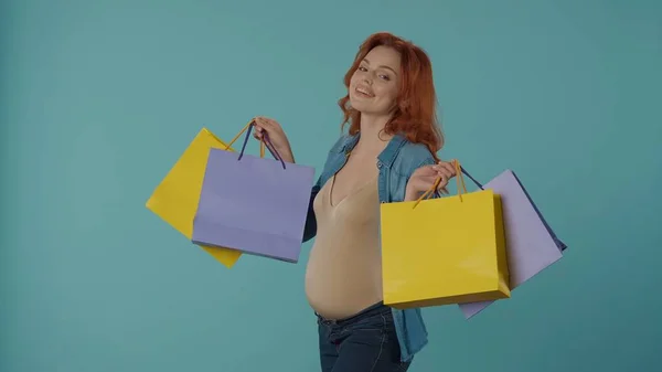 カラフルなショッピングバッグを閉じた幸せな妊婦の肖像画 妊娠中の女性はブルーで孤立しました 母性と妊娠の概念 — ストック写真
