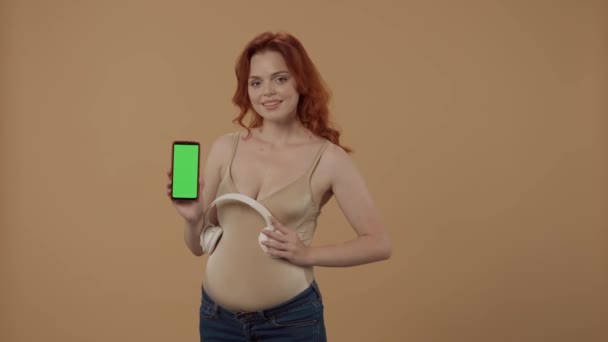 Una Mujer Embarazada Puso Auriculares Inalámbricos Blancos Estómago Sostiene Teléfono — Vídeo de stock