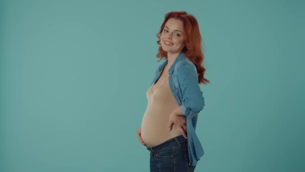 Eine Rothaarige Schwangere Streicht Lächelnd Über Ihren Aufgeblähten Bauch Wird — Stockvideo
