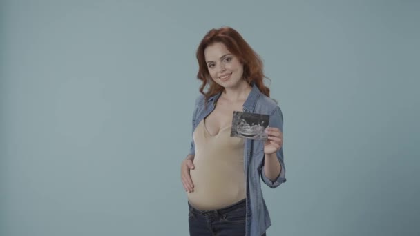 Eine Schwangere Frau Hält Ein Ultraschallbild Der Hand Und Streicht — Stockvideo
