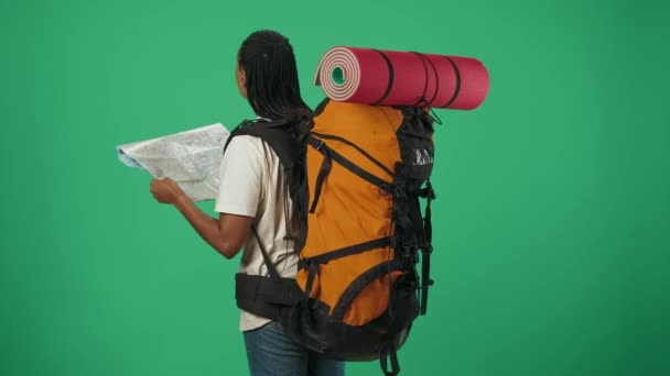 女旅行者拿着纸质地图 看着上面的标牌 找到方向 一个身穿休闲装背包的女游客的画像 在业余时间旅行的概念 在绿上被隔离 — 图库视频影像