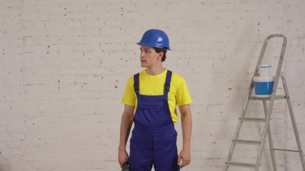 Średni Film Młodego Pracownika Budowlanego Stojącego Remontowanym Pomieszczeniu Podnoszącego Wiertarkę — Wideo stockowe