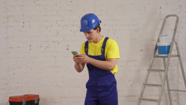 Vídeo Médio Trabalhador Construção Sala Segurando Smartphone Esperando Resposta Seguida — Vídeo de Stock