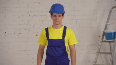 Genç bir inşaat işçisinin elinde kredi kartıyla odada dikilip ürünü tavsiye ederken çekilmiş orta ölçekli videosu. Ürün, alım, şirket reklamı.