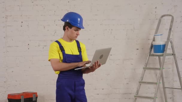 一个年轻的建筑工人站在房间里 拿着笔记本电脑 环顾四周的中等视频 制造商 公司广告 — 图库视频影像