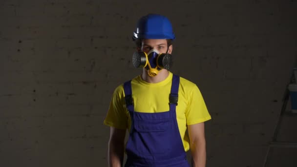 煙で満たされた部屋に立っている建設作業員の中型ビデオは 呼吸器を着用して親指を上げて喜んでいます 安全対策 メーカー 企業広告 — ストック動画