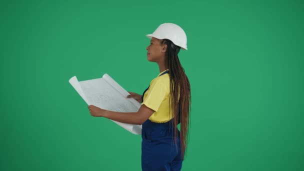 中绿色屏幕隔离了一个深色皮肤的年轻女建筑工人的关键视频 她正在研究和比较她的计划与周围环境 维修广告 可靠性 — 图库视频影像