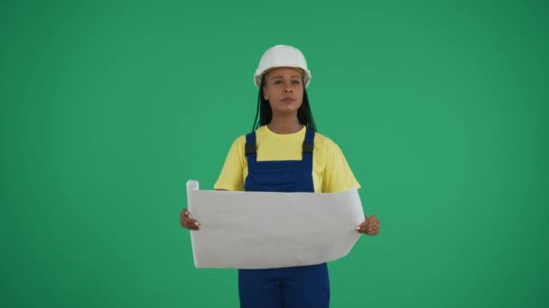 中グリーンスクリーンは 暗い肌の若い女性建設労働者のクロマキービデオを 彼女の計画を周囲と比較して分離しました 修理広告について 信頼性について — ストック動画