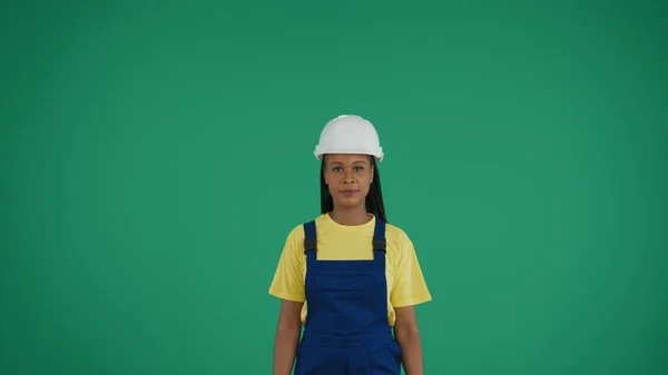 中緑色のスクリーンはリラックスした一見のカメラを見ている暗い肌の若い女性建設労働者のクロマキービデオを隔離しました 広告について 信頼性 信頼性 — ストック写真