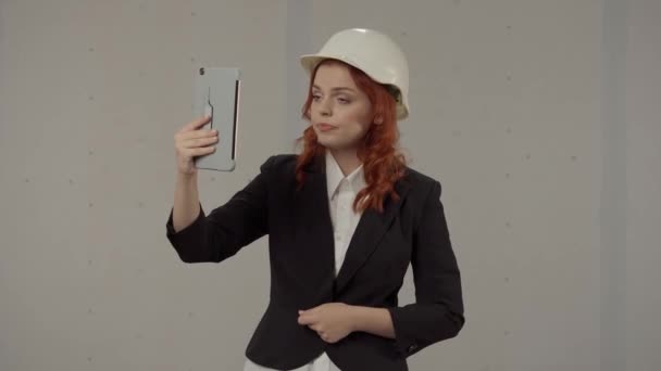 女建筑师在电视上说话 戴着保护头盔穿着紧身衣的女商人们穿着灰色背景的工作服 — 图库视频影像