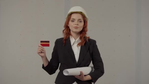 女建筑师持借记卡 发薪日 戴着保护头盔 在工作室里有灰色背景蓝图的女商人 — 图库视频影像