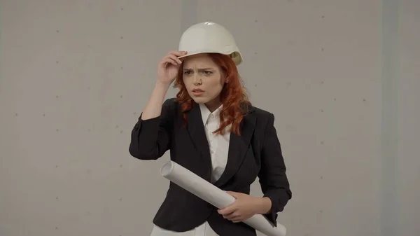 女建筑师绝望地 震惊地 绝望地抱头 一个戴着保护头盔 头戴灰色背景的工作室蓝图的沮丧女人的画像 — 图库照片