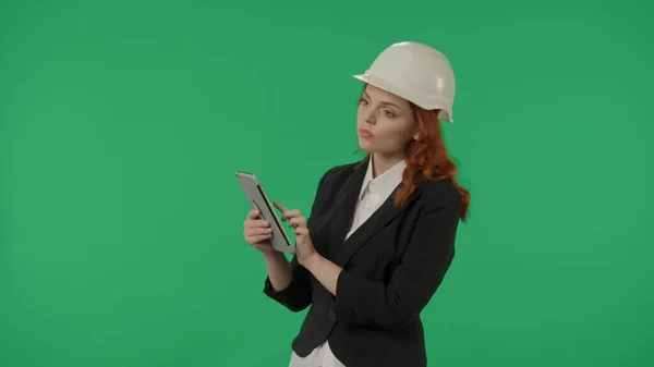 女性建築家がオブジェクトの検査を行い タブレットにノートを取ります 保護ヘルメットとスタジオの緑色のスクリーンのタブレットでビジネス女性 — ストック写真