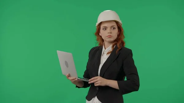 保護ヘルメットの女性建築家で スタジオの緑色のスクリーンの背景にラップトップを持っています 広告エリア ワークスペースモックアップ — ストック写真