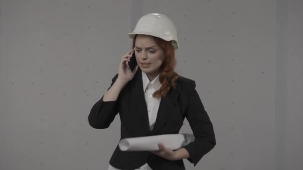 건축가가 스마트폰에서 비명을 지르며 말합니다 헬멧과 엄격한 양복을 비즈니스 여성과 — 비디오
