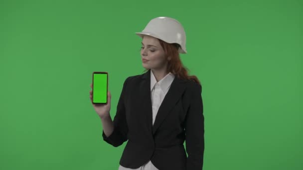 女性アーキテクトはグリーンスクリーンスマートフォンを表示します スタジオのグリーンスクリーンの背景にあるヘルメットのビジネス女性の肖像画 広告区域 ワークスペースHdr Bt2020 Hlg材料 — ストック動画