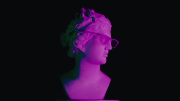 紫色の光のガラスで古代の女神金星大理石像のクローズアップショット プラットフォーム上で回転するロマン時代の女性バストの肖像画 ブラックバックで孤立 クリエイティブな抽象概念 — ストック動画