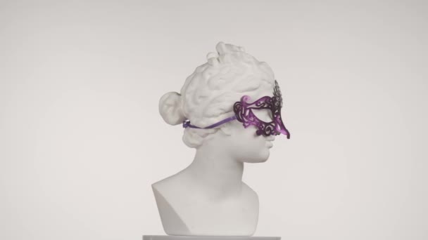 カーニバルアイマスクの美しい古代の女神金星大理石像のクローズアップショット ロマン時代の肖像画 プラトフォルムで回転する女性バスト 白い背景に孤立した クリエイティブな抽象概念 — ストック動画