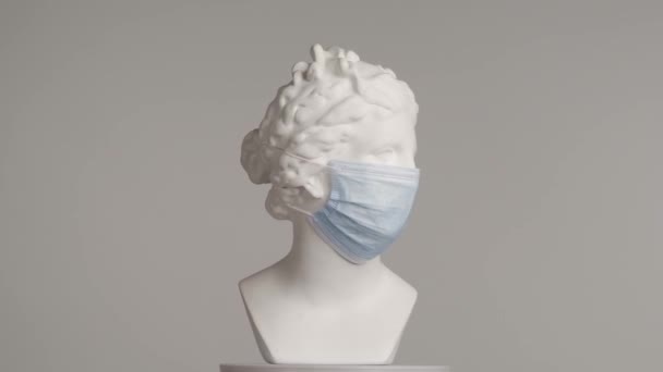 用医用面罩拍摄美丽的古代女神维纳斯大理石雕像 罗马时代女性半身像的肖像在平台上旋转 被灰色背景隔离 富有创意的抽象概念 — 图库视频影像