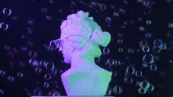 眼鏡で古代の女神像のクローズアップショット 石鹸の泡が飛び回っています ネオンライトのプラットフォームで回転するロマン時代の女性バストの肖像画 創造的な抽象概念 Hdr Bt2020 Hlgについて — ストック動画