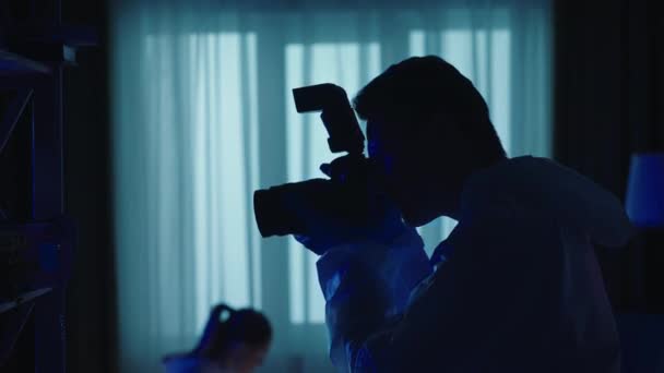 法医学の科学者チームは 警察のサイレンから青色の赤色光で照らされた暗いアパートで 犯罪現場の証拠を収集します 女性は凶器 ナイフを検査する 男は写真を撮る — ストック動画