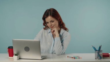 Doymuş, mutlu ve rahat bir genç kadının dizüstü bilgisayarına bakarken orta izole edilmiş görüntüsü. Barışçıl bir şekilde çalışıyor, bir şeyler düşünüyor ve eline yaslanıyor. Yaratıcı içerik.