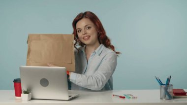 Tatmin olmuş, mutlu ve rahat genç bir kadının teslimat paketini tutarken ve kameraya mutlu bir şekilde gülümserken orta derece izole edilmiş görüntüsü. Teslimat servisi reklamı.