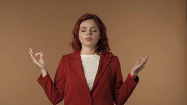 Gevşemiş, mutlu genç bir kadının metitasyon jesti ve derin nefes alıp verirken orta derecede izole edilmiş görüntüsü. Kadın sakinleşmek için Mudra ve nefes alıyor. Yaratıcı içerik veya reklam