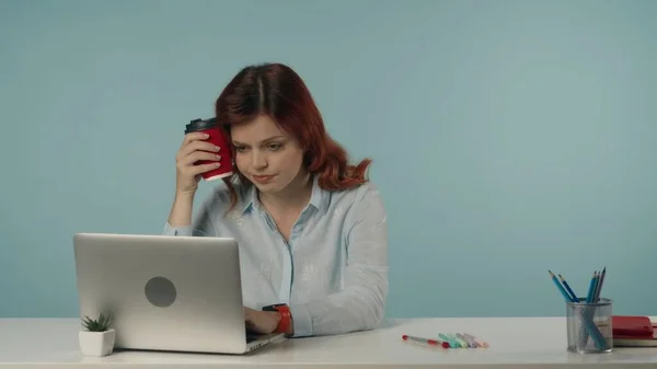 一个疲惫疲惫的年轻女人看着她的笔记本电脑屏幕 拍了一张中等的孤立的照片 她心平气和地工作着 手里拿着一杯咖啡 创意内容或广告 — 图库照片