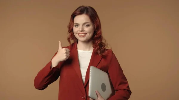 一个年轻女子对着相机微笑 腋下夹着笔记本电脑 竖起大拇指 拍了一张中等的孤立的照片 工作环境 创意商业内容或广告 — 图库照片