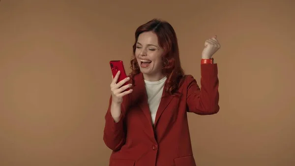 彼女の手にスマートフォンを握っている若い女性の中程度隔離されたショットは 受け取った幸運なニュースに喜んで反応します 成功した取引 ビジネス広告 — ストック写真