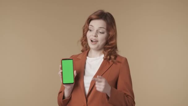 Среднее Изолированное Видео Молодой Женщины Перед Камерой Указывающей Телефон Макетом — стоковое видео