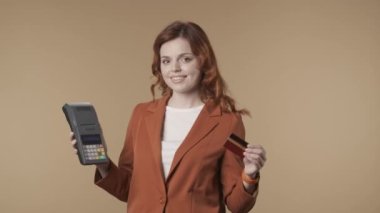 Keyifli, tatmin olmuş ve rahat genç bir kadının elinde bir terminal tutarken ve ödemeyi tamamlamak için kredi kartına bastığını gösteren orta ölçekli bir video. Ticaret ve bankacılık reklamı. HDR BT2020