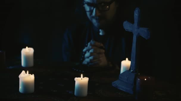 その上に魔法の道具でテーブルをキャプチャするビデオ 司祭は手でビーズを持ってテーブルに座り 目を閉じて祈り 不安に動き出しています クリエイティブコンテンツ ハロウィーン — ストック動画